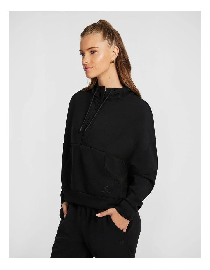 Rockwear Travel Hip Hood Half Zip in Black, featuring a cozy hood and front pockets for a relaxed, stylish look.