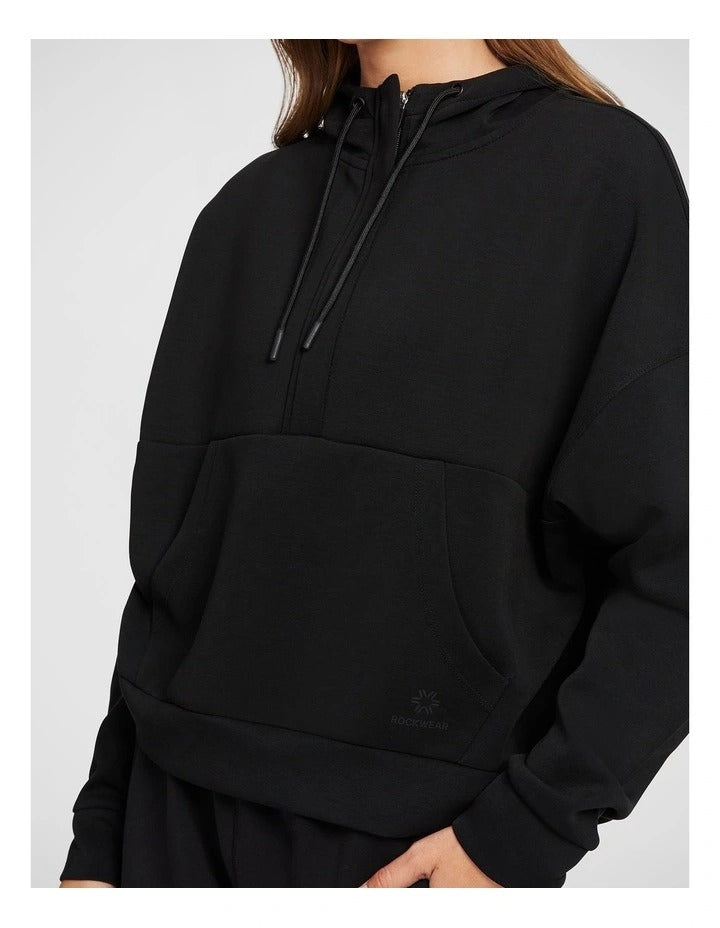 Rockwear Travel Hip Hood Half Zip in Black, featuring a cozy hood and front pockets for a relaxed, stylish look.