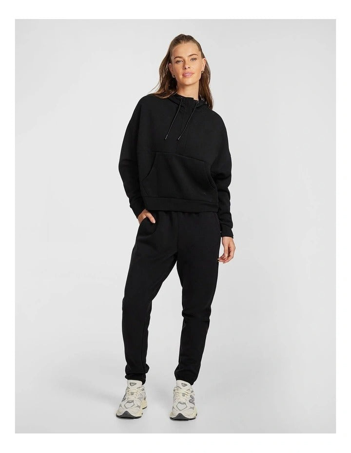 Rockwear Travel Hip Hood Half Zip in Black, featuring a cozy hood and front pockets for a relaxed, stylish look.