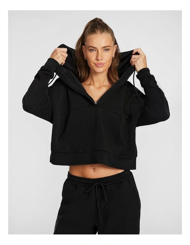 Rockwear Travel Hip Hood Half Zip in Black, featuring a cozy hood and front pockets for a relaxed, stylish look.