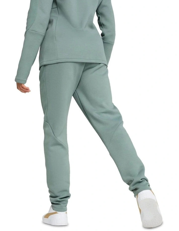 Person wearing a light green tracksuit with white sneakers on a white background
