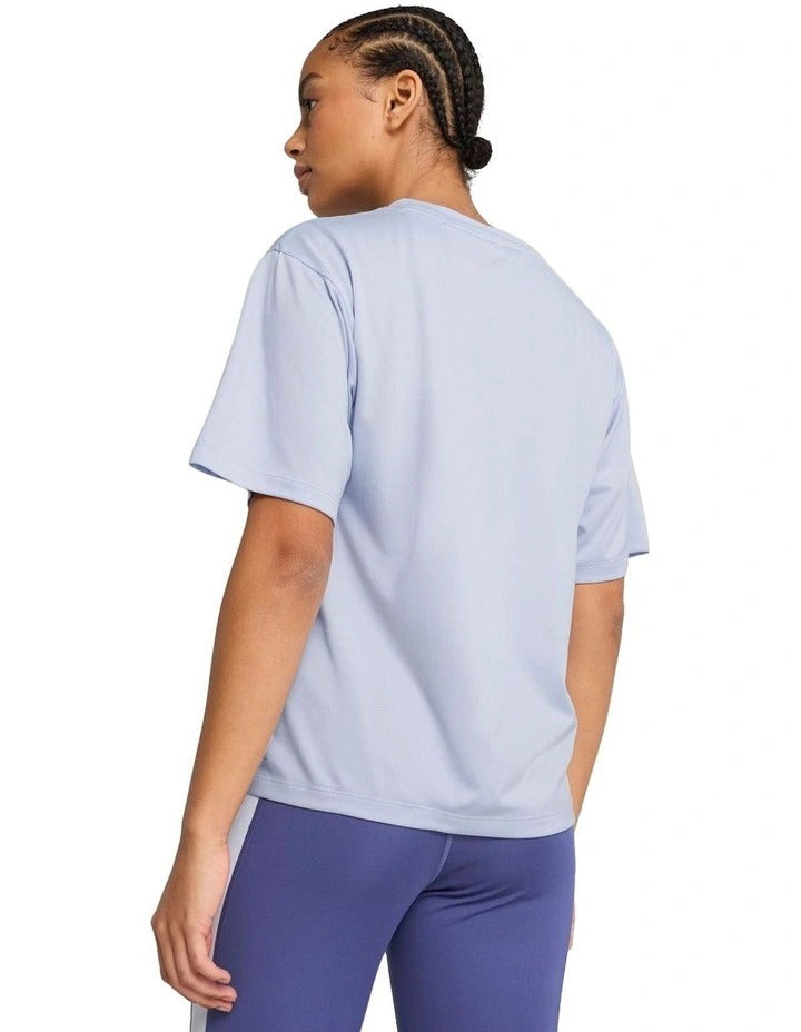 Woman wearing a light blue athletic shirt and purple leggings holding a black kettlebell on a white background