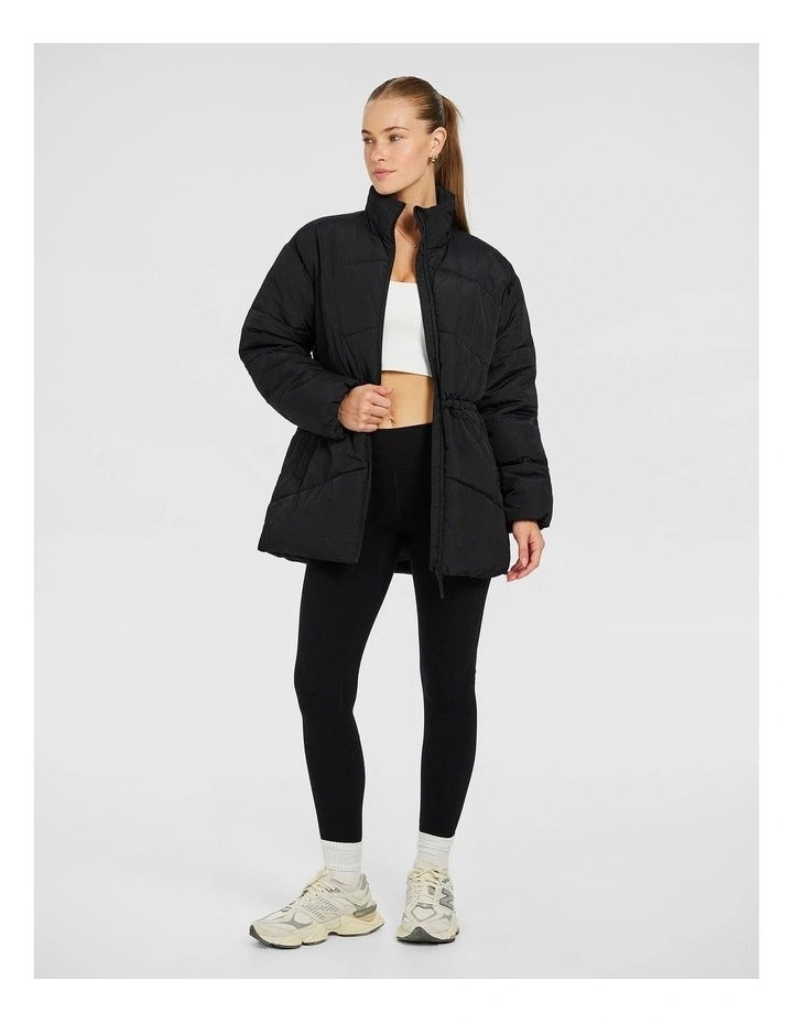 Rockwear Longline Puffer Jacket in Black, women's padded jacket with side phone pockets and a flattering cinched waist for warmth and style.