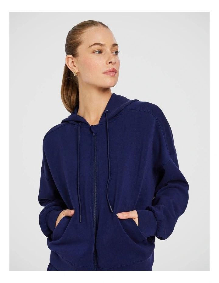 Rockwear Travel Zip Through Hoodie in Blue, featuring a relaxed fit, hip-length silhouette, and side pockets for a cozy, stylish look.