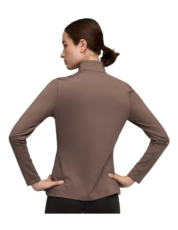 Woman wearing a brown athletic jacket and black leggings with a duffel bag on a white background