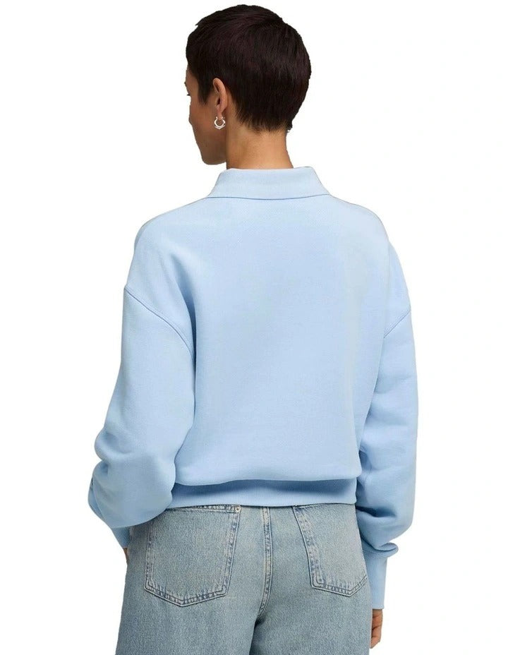 Person wearing a light blue Puma sweatshirt on a white background