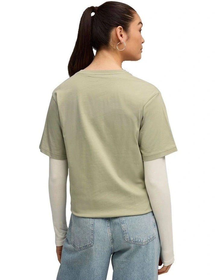 Woman wearing a green t-shirt with a brand logo on a white background