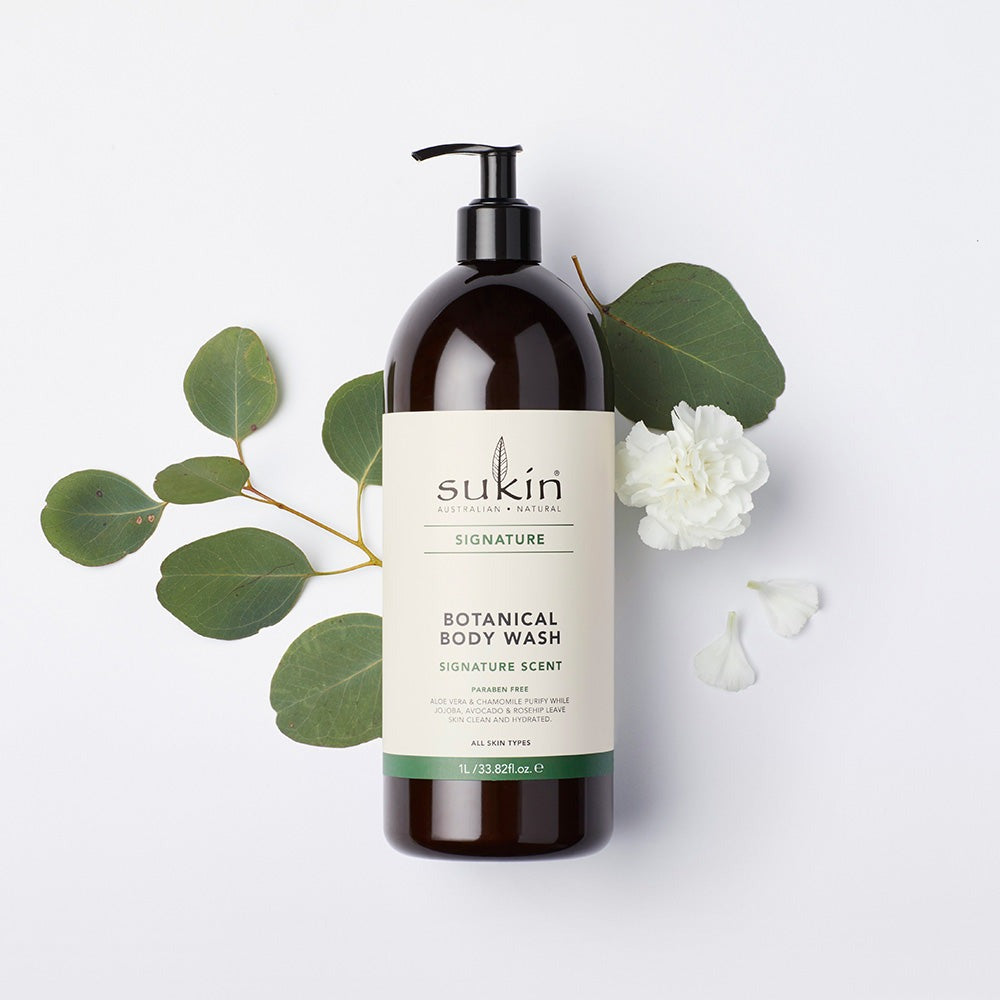 Sukin Botanical Body Wash bottle with green leaves and white flowers on a light background