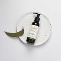 Sukin facial moisturizer bottle on a white background with a eucalyptus leaf.