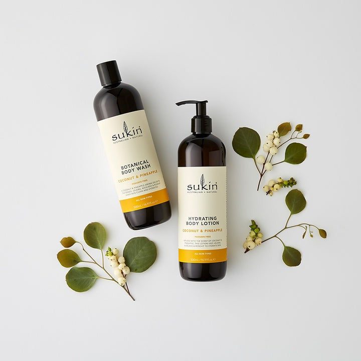 Two Sukin body care products with green leaves on a light background