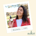 Woman holding a bottle of Sukin product outdoors with a blurred background
