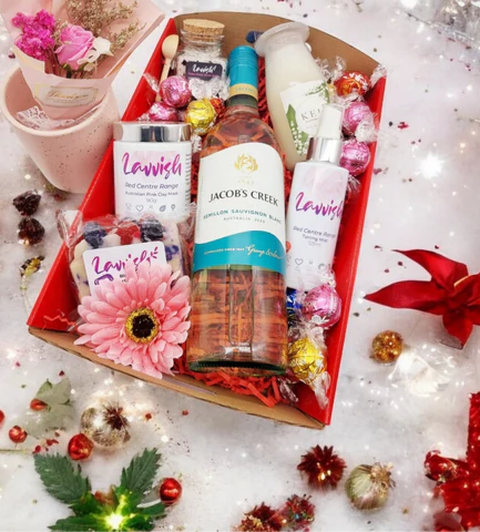 Lavvish Pamper Pack with wine bottle, skincare products, chocolates, and floral decorations in a festive gift box