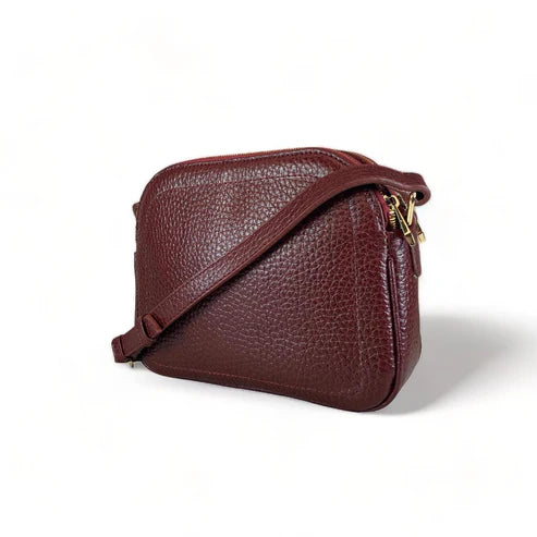 Red leather women’s shoulder bag with three compartments, elegant small satchel design featuring adjustable strap and gold hardware.