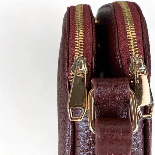 Red leather women’s shoulder bag with three compartments, elegant small satchel design featuring adjustable strap and gold hardware.