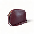 Red leather women’s shoulder bag with three compartments, elegant small satchel design featuring adjustable strap and gold hardware.