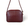 Red leather women’s shoulder bag with three compartments, elegant small satchel design featuring adjustable strap and gold hardware.