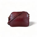 Dark red crocodile-embossed leather shoulder bag with gold hardware and adjustable crossbody strap, luxury women’s handbag on white background.