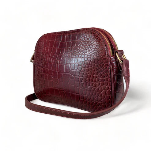 Dark red crocodile-embossed leather shoulder bag with gold hardware and adjustable crossbody strap, luxury women’s handbag on white background.