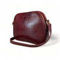 Dark red crocodile-embossed leather shoulder bag with gold hardware and adjustable crossbody strap, luxury women’s handbag on white background.