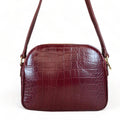 Dark red crocodile-embossed leather shoulder bag with gold hardware and adjustable crossbody strap, luxury women’s handbag on white background.