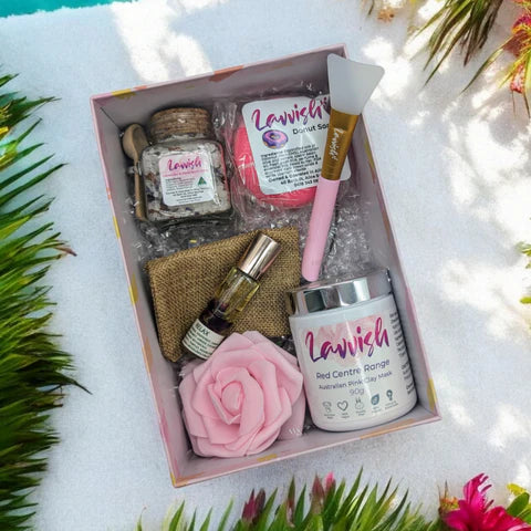 Lavvish Relax self-care gift box with skincare products, bath salts, donut soap, face mask brush, and rose decor displayed on tropical background