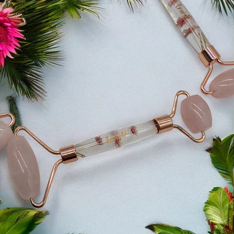 Lavvish Rose Quartz Facial Roller with box displayed on iridescent stand surrounded by small potted succulents