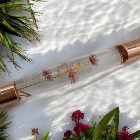 Lavvish Rose Quartz Facial Roller with box displayed on iridescent stand surrounded by small potted succulents