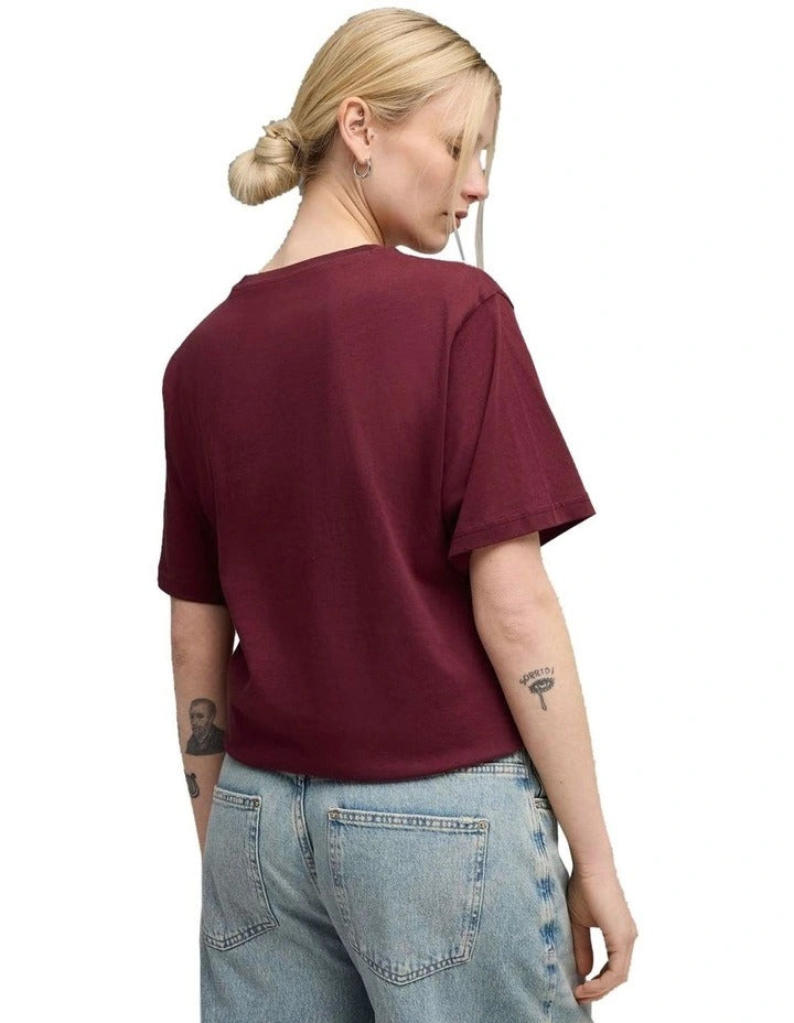 Person wearing a maroon t-shirt with a logo on a white background