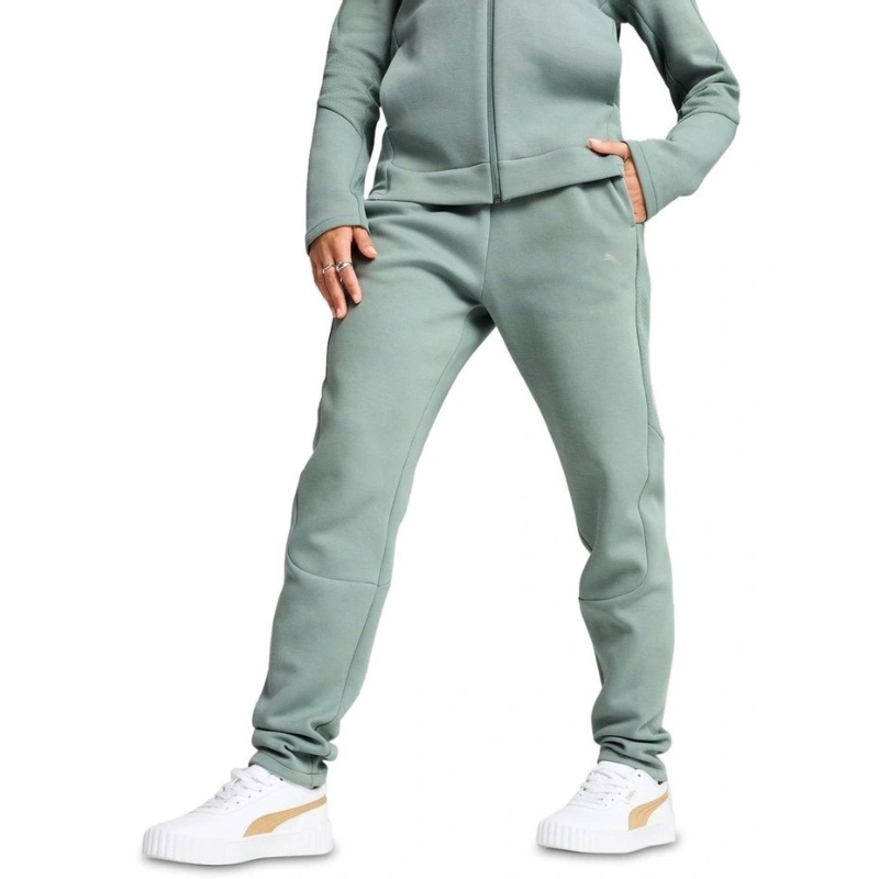 Person wearing a light green tracksuit with white sneakers on a white background