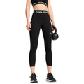 Person wearing black Puma leggings and sports bra holding a kettlebell on a white background