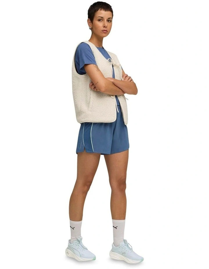 Person wearing blue athletic shorts with a visible brand logo on a white background