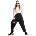 Person wearing black Puma pants and a white tank top, holding a black Puma handbag on a white background.