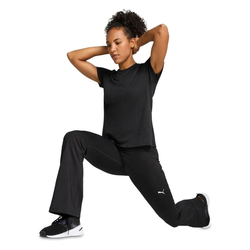 Woman in black athletic wear with a visible brand logo, posing against a white background