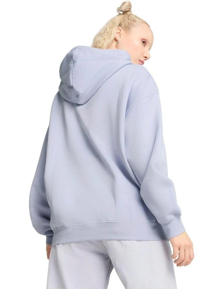 Person wearing a light blue hoodie with a brand logo, standing against a plain background