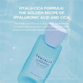 Blue skincare bottle with text about hyalu-cica formula on a light blue background