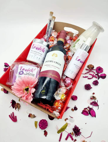 Lavvish Pamper Pack with wine bottle, skincare products, chocolates, and floral decorations in a festive gift box