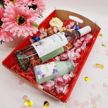 Purple Lavvish self-care gift box with skincare products, bath salts, soap bar, facial roller, and bath bomb displayed on purple floral background
