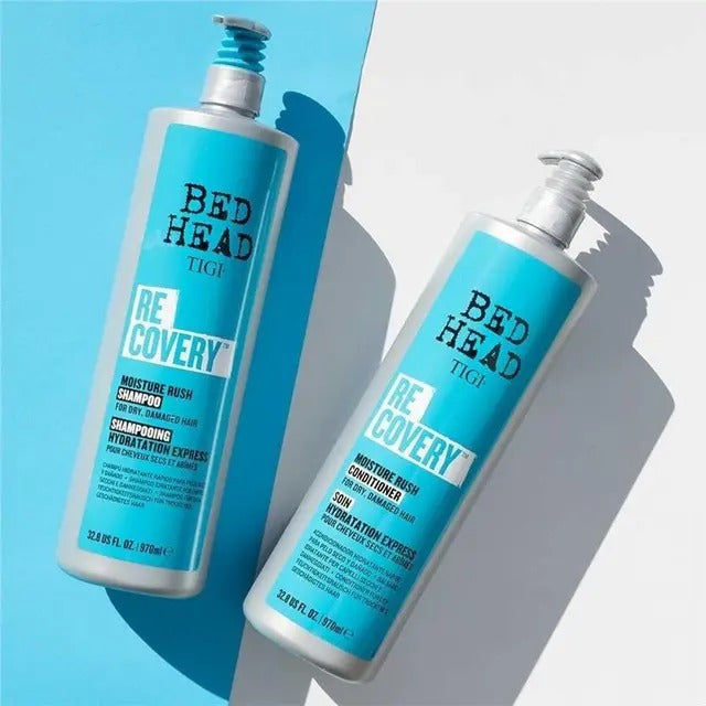 Two bottles of Bed Head Re:Cover shampoo and conditioner on a light blue and white background