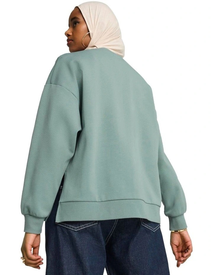 Woman wearing a green Puma sweatshirt with a beige hijab on a white background