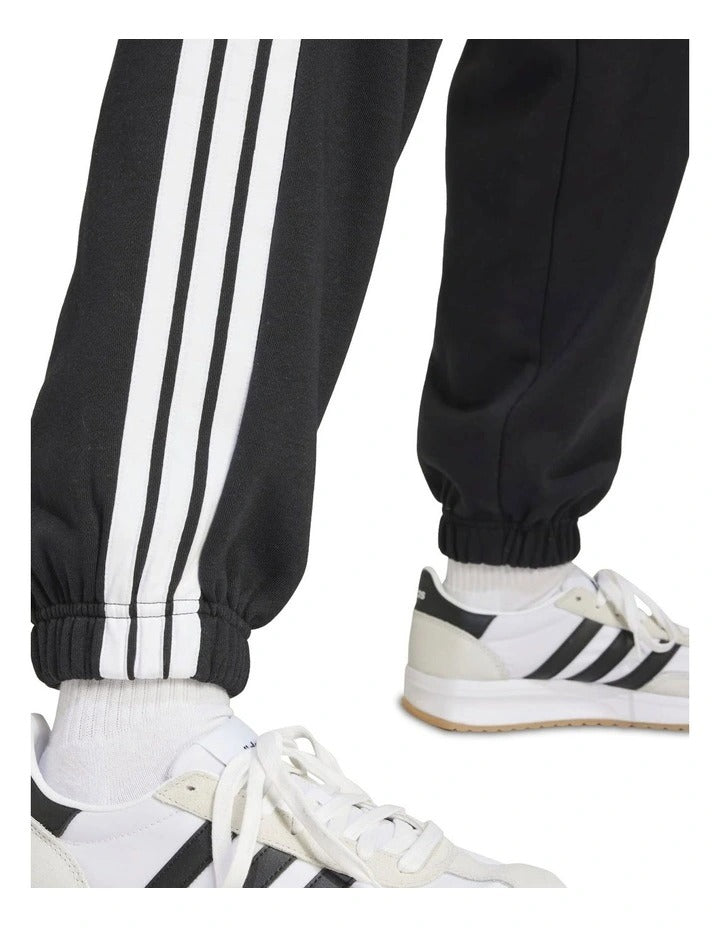 Adidas Essentials 3-Stripes Fleece Loose-Fit Joggers in grey, cozy casual pants with iconic side stripes, made from recycled cotton and polyester blend