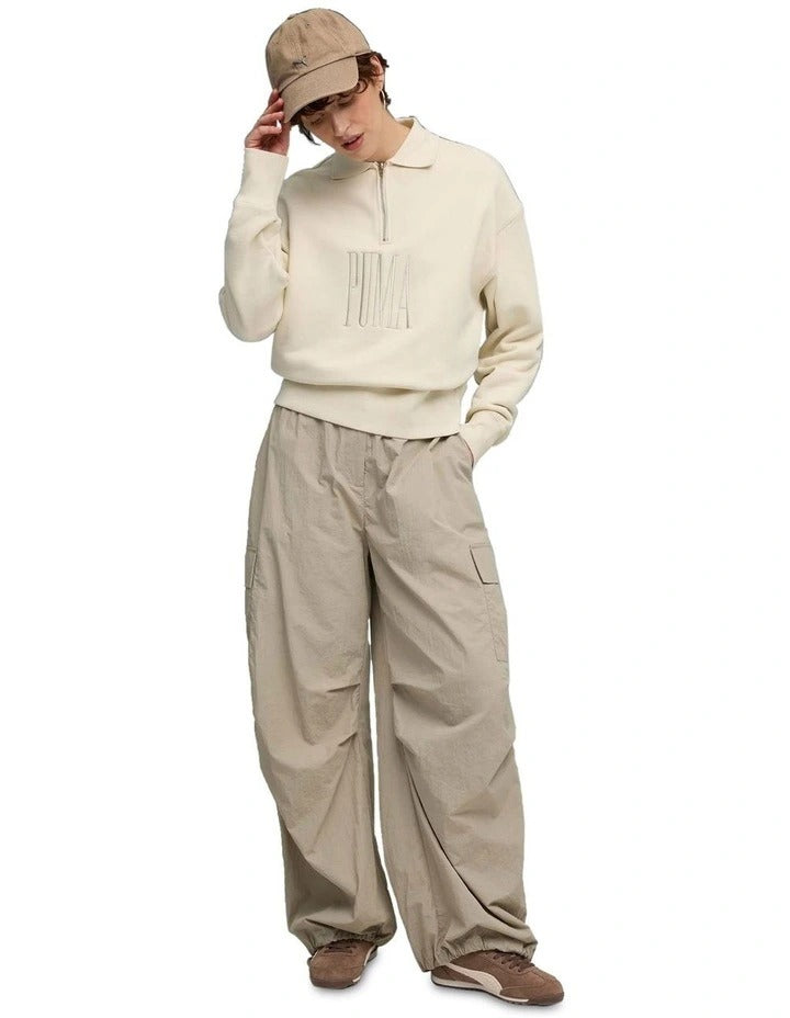 Person wearing a beige sweater with text and matching pants on a white background