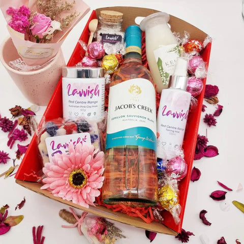 Lavvish Pamper Pack with wine bottle, skincare products, chocolates, and floral decorations in a festive gift box