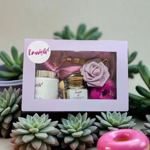 Sleep and Unwind Lavvish gift box with pink eye mask, lavender bath salts, skincare items, and floral soap surrounded by succulents