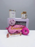 Sleep and Unwind Lavvish gift box with pink eye mask, lavender bath salts, skincare items, and floral soap surrounded by succulents
