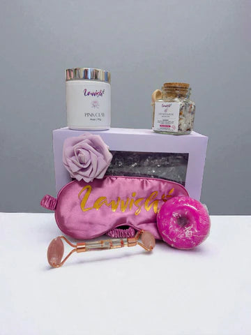 Sleep and Unwind Lavvish gift box with pink eye mask, lavender bath salts, skincare items, and floral soap surrounded by succulents