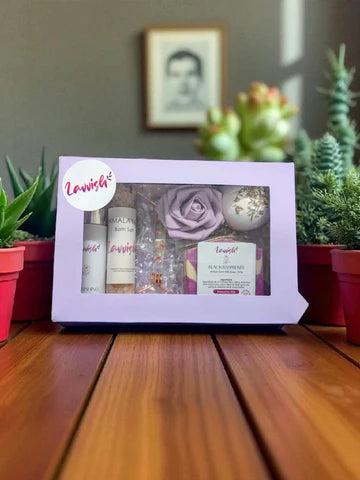Purple Lavvish self-care gift box with skincare products, bath salts, soap bar, facial roller, and bath bomb displayed on purple floral background
